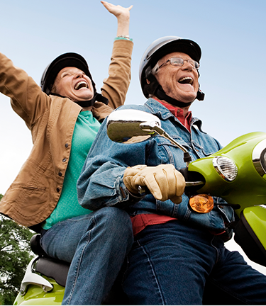 Vested employee enjoying his retirement with his wife while riding a Vespa